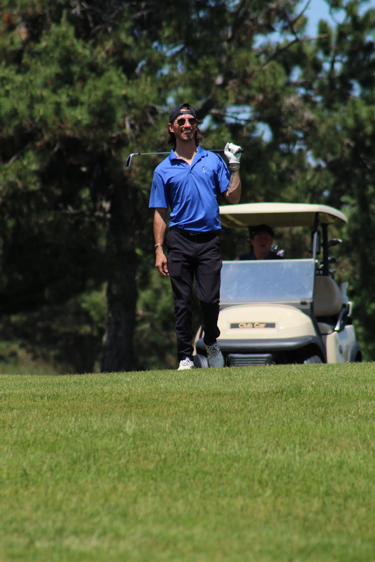 Golfer smiling with a club near a cart during an outing