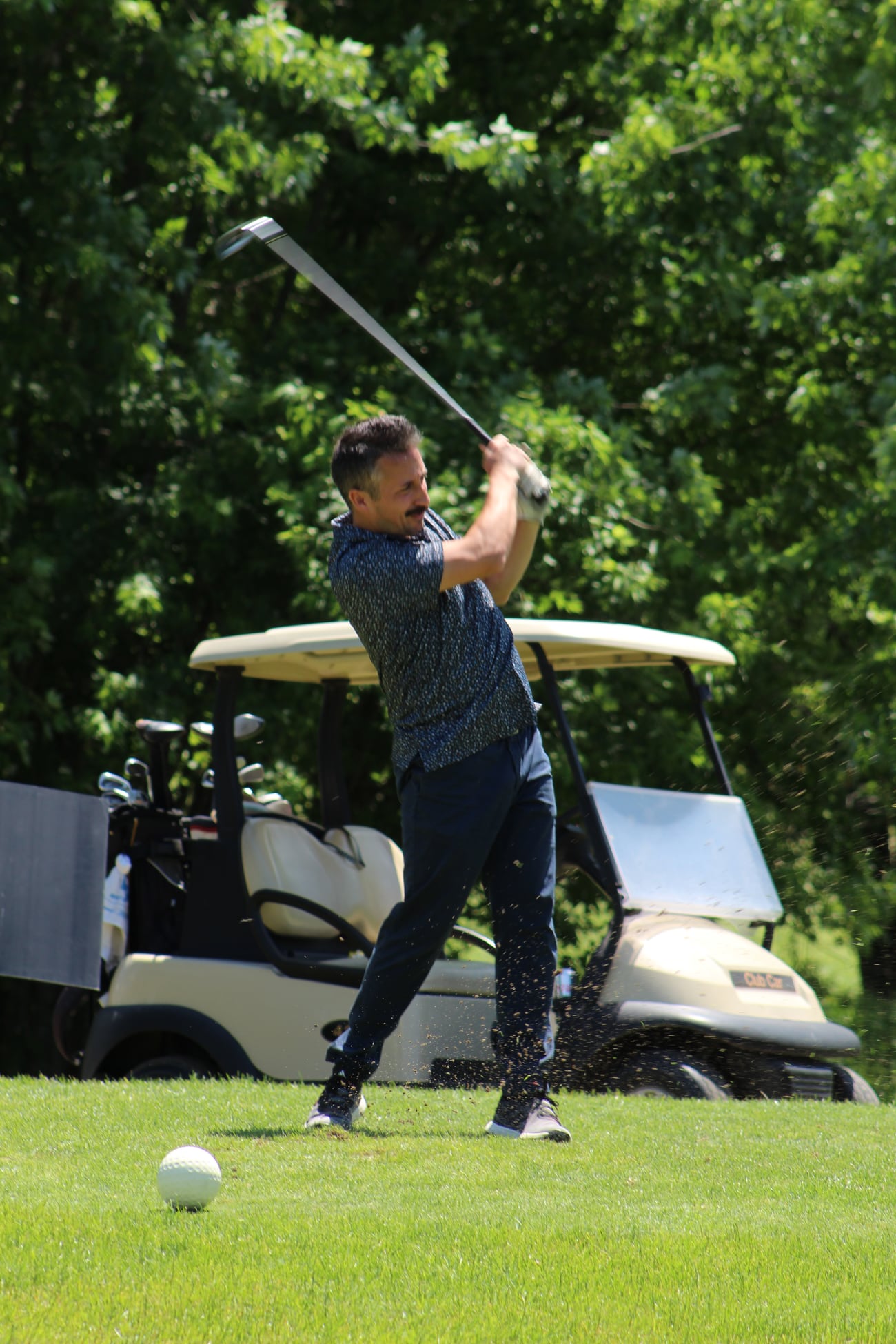 Golfer hitting a shot near a cart