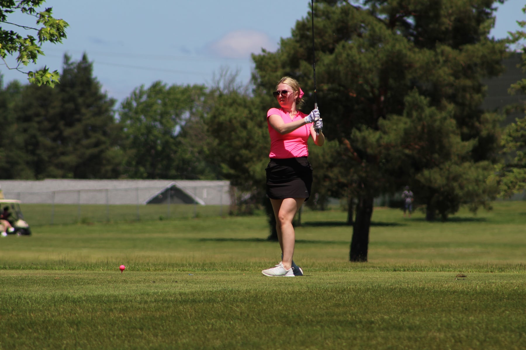 Golfer in pink following through on the tee